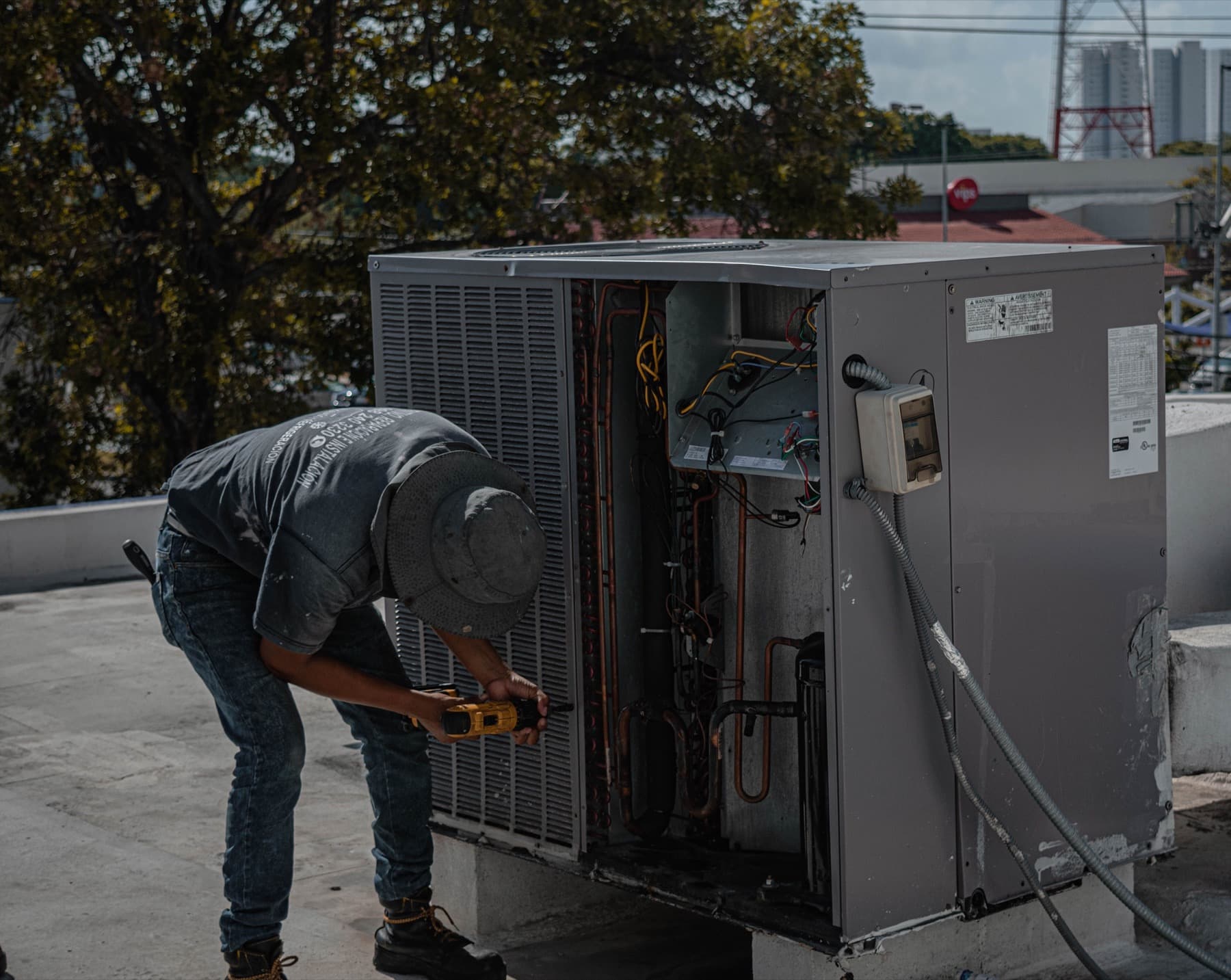 HVAC technician servicing a rooftop condenser unit in daylight